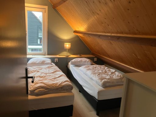 Slaapkamer Kamer met twee eenpersoonsbedden en houten plafond, verlicht door een lamp.