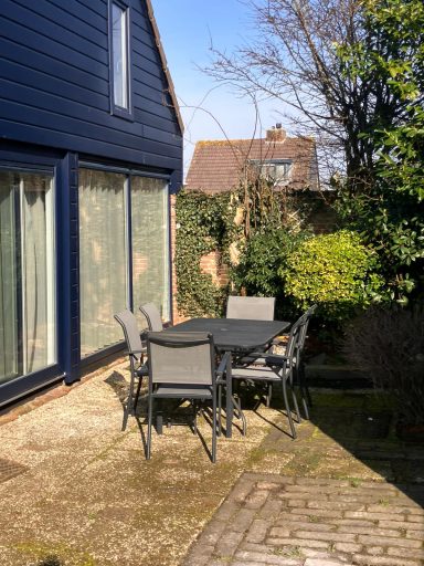 Tuin met tuintafel Zwarte tuintafel met stoelen in een zonnige tuin naast een huis.