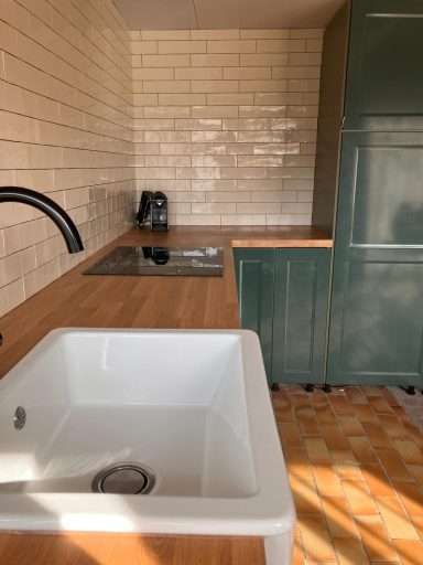 Keuken Moderne keuken met houten werkblad, witte spoelbak en groene kast.