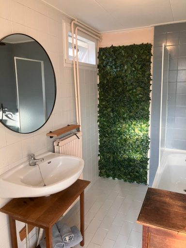 Badkamer Badkamer met een ronde spiegel, wastafel en een groene wand.