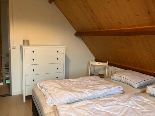 Slaapkamer Slaapkamer met houten muren, twee eenpersoonsbedden en een witte commode.