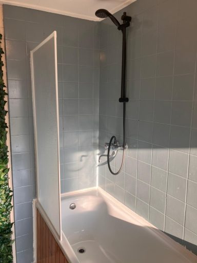 Badkamer Badkamer met een douche en een ligbad tegen een denim blauwe wand.