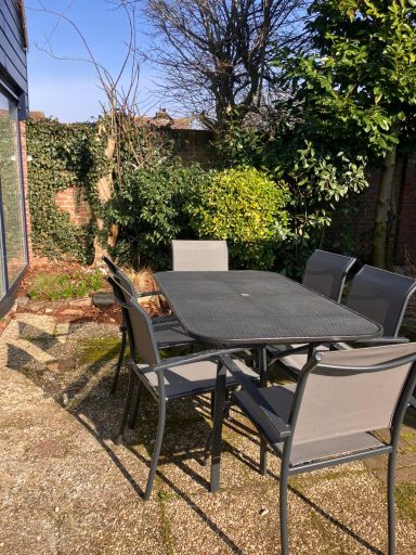 Tuin met tuintafel Een tuintafel met zes stoelen, omringd door groen en bomen.