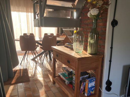 Woonkamer Houten bijzettafel met boeken en bloemen, in een lichte woonkamer met een eetgedeelte.